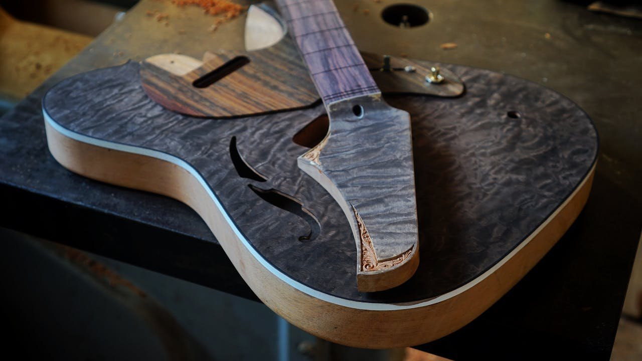 Detailed photograph of an unfinished wooden guitar body on a workshop table, showcasing craftsmanship.