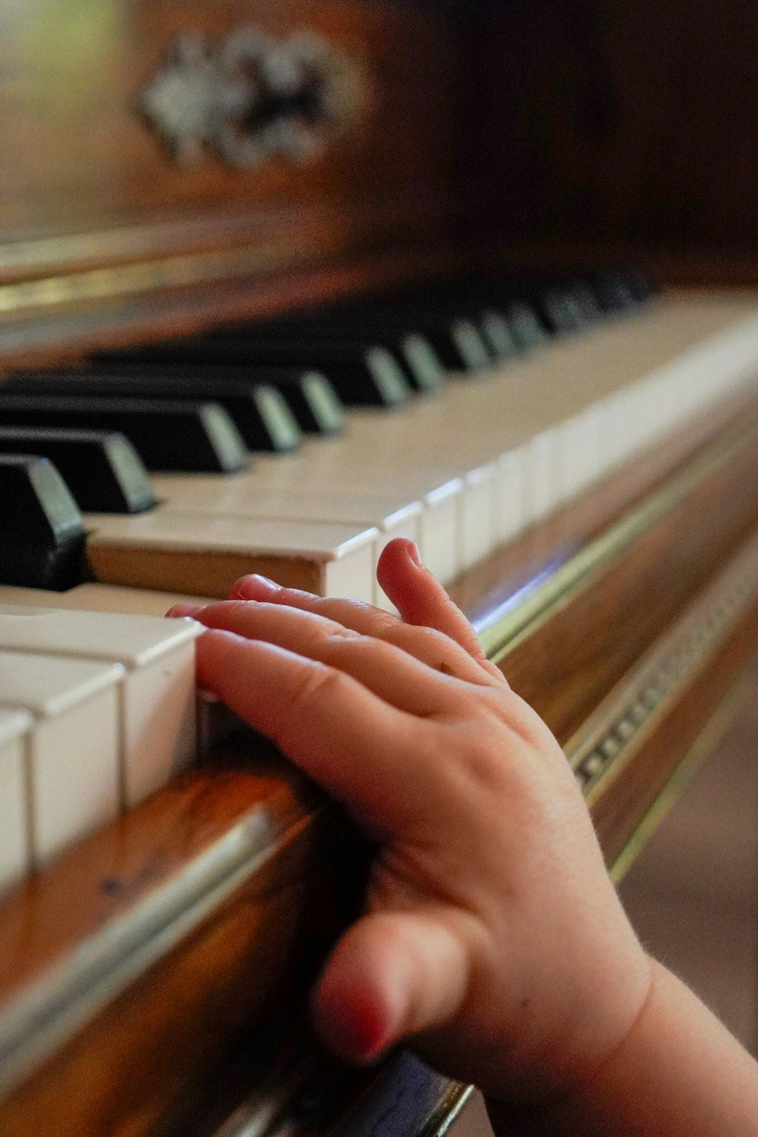 a-childs-hand-rests-on-a-piano-keyboard-58vozwsh8ra