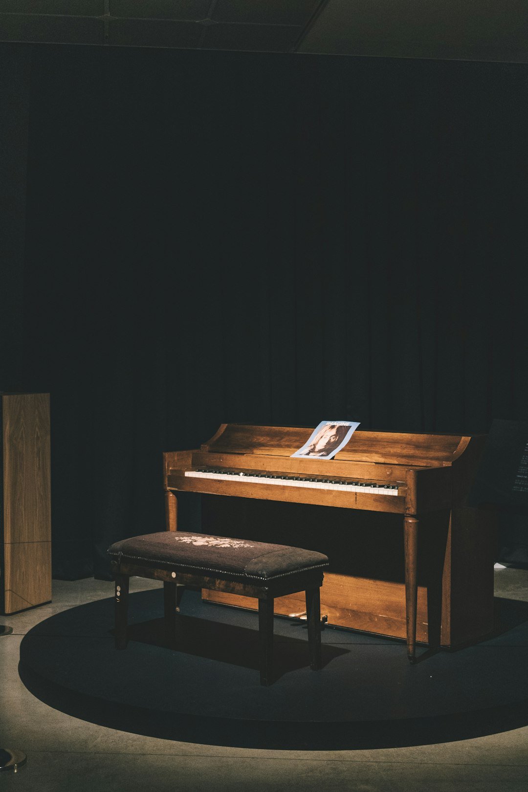 brown-wooden-upright-piano-with-ottoman-bench-and-light-turned-on-lk-ewcftuiy