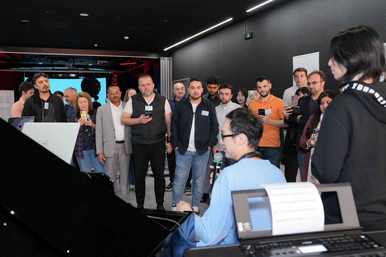 A diverse group of adults attentively watching a piano demonstration indoors.