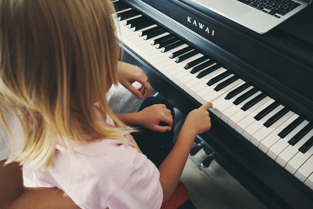 young-girl-plays-piano-with-laptop-nearby-e6pfonpnzwa